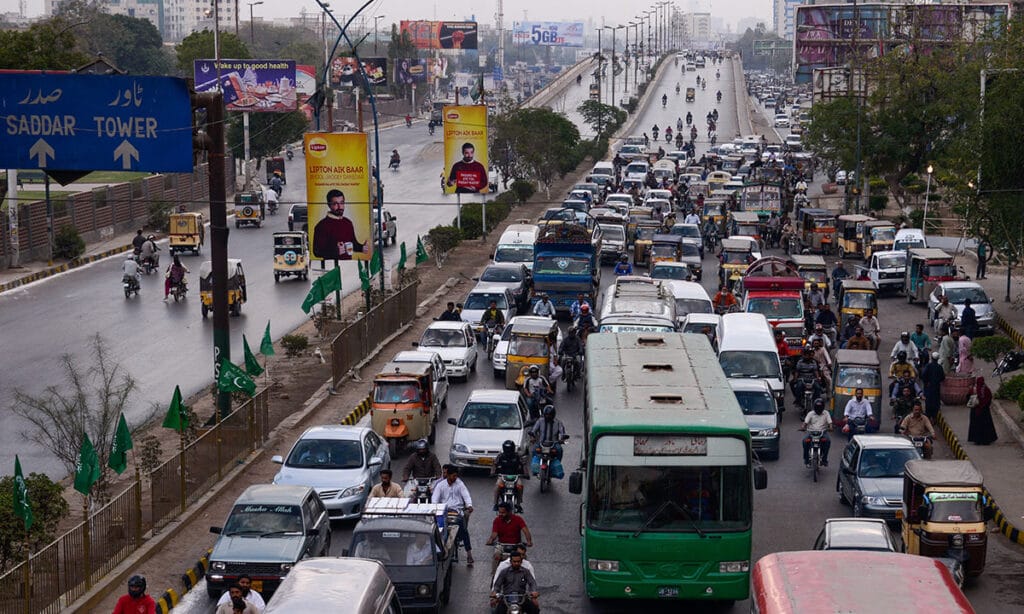 A bustling Karachi street showing public transport or ride-hailing apps in use.