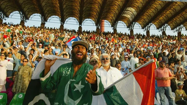 A photo of enthusiastic fans waving Pakistani flags in Gaddafi Stadium.