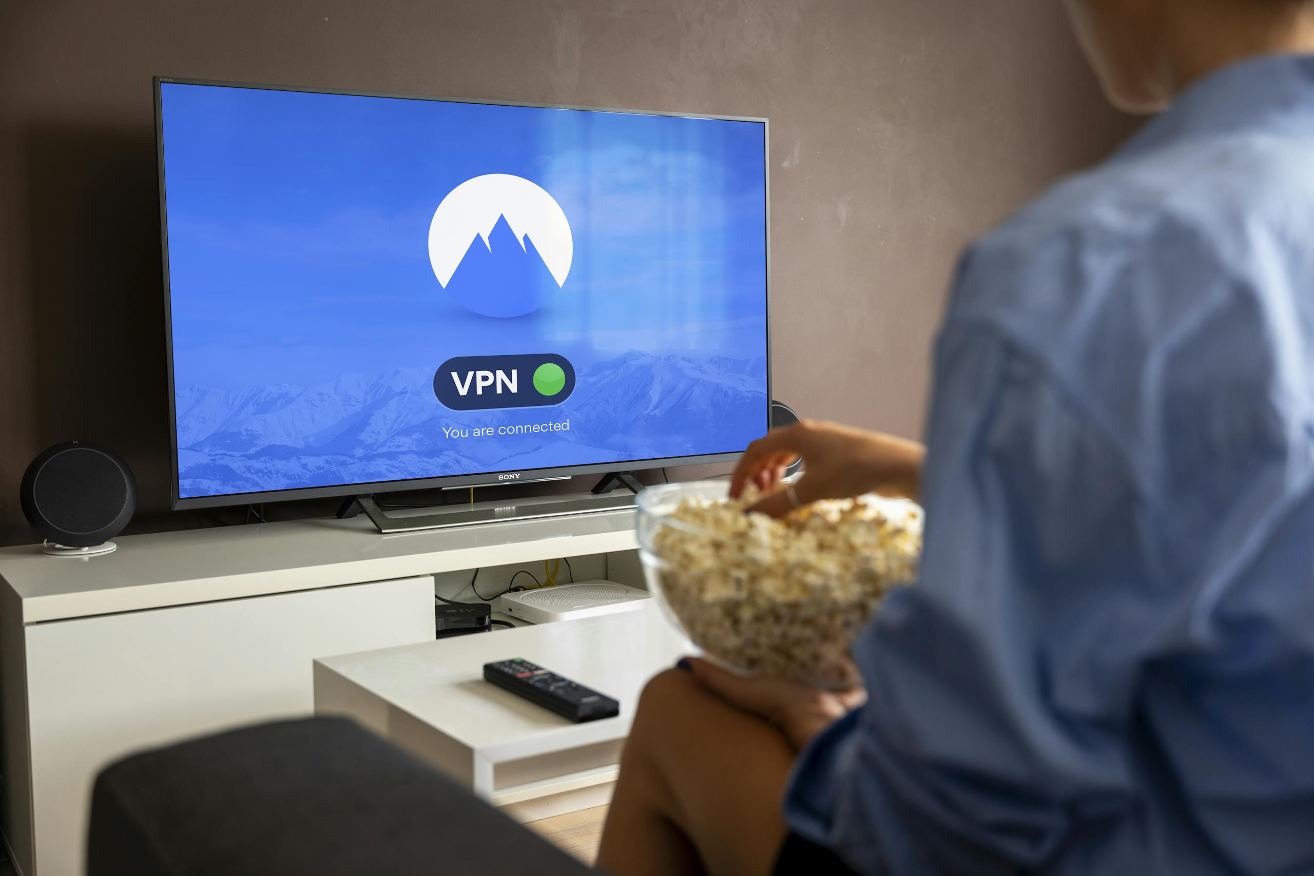 A relaxed scene at home with a person enjoying popcorn while watching a VPN-protected TV.